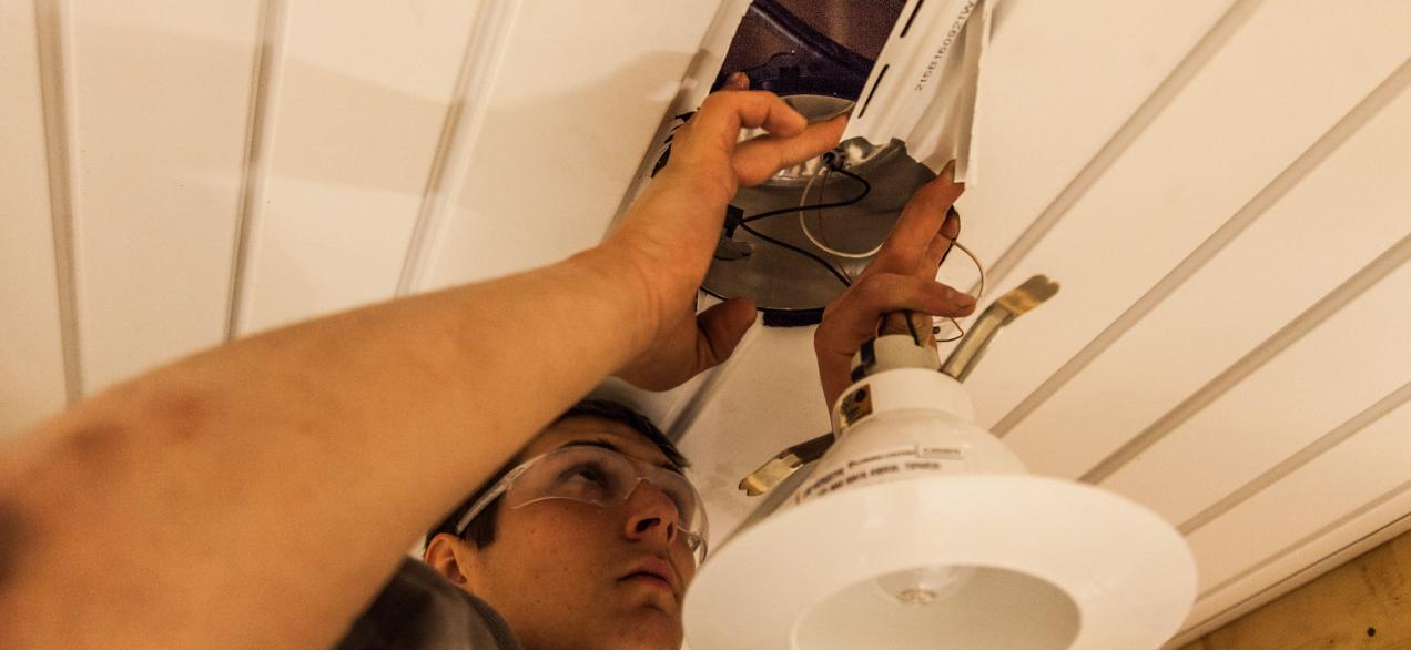 Image of student installing lighting fixture 