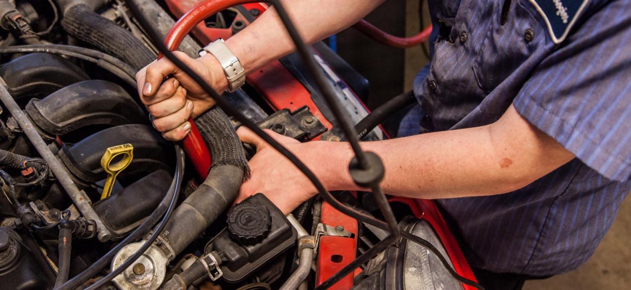 Image of student working under the hood of a red car