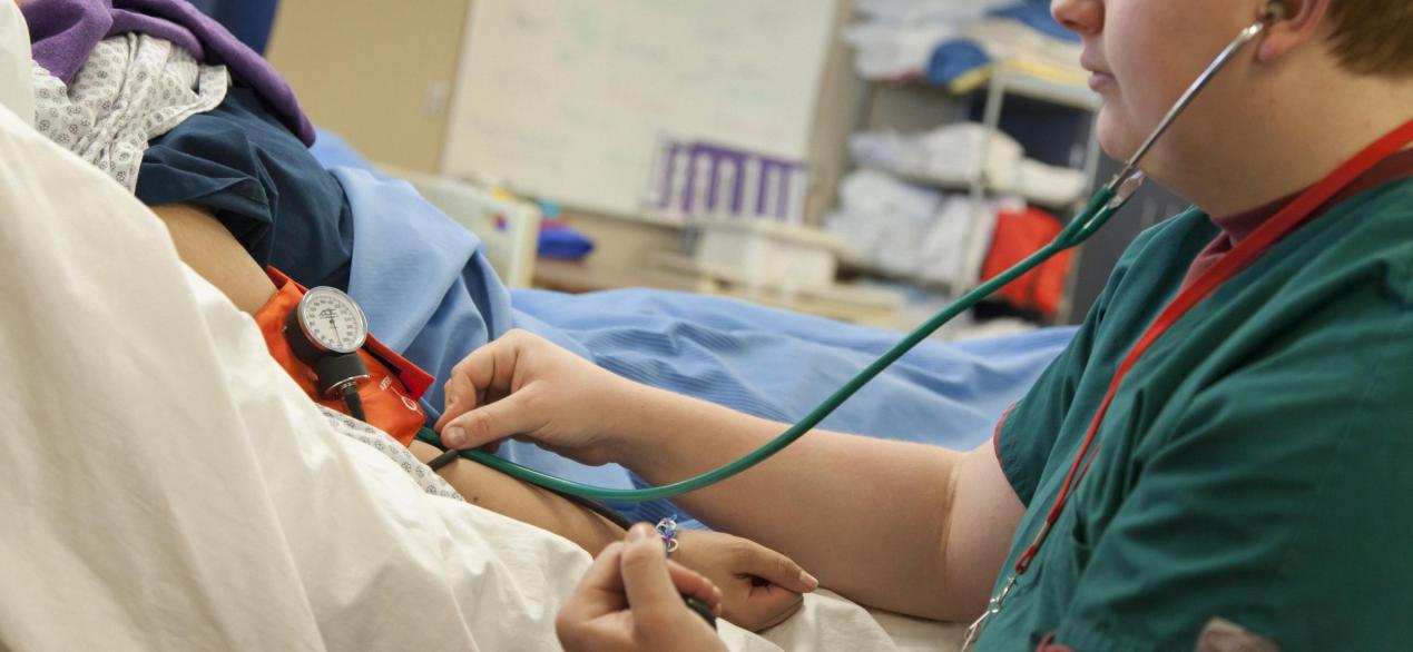 Image of a student taking a patient's blood pressure