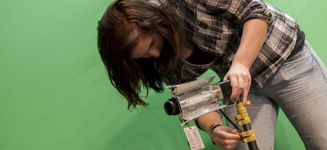 Image of student working with lighting in the green screen room 