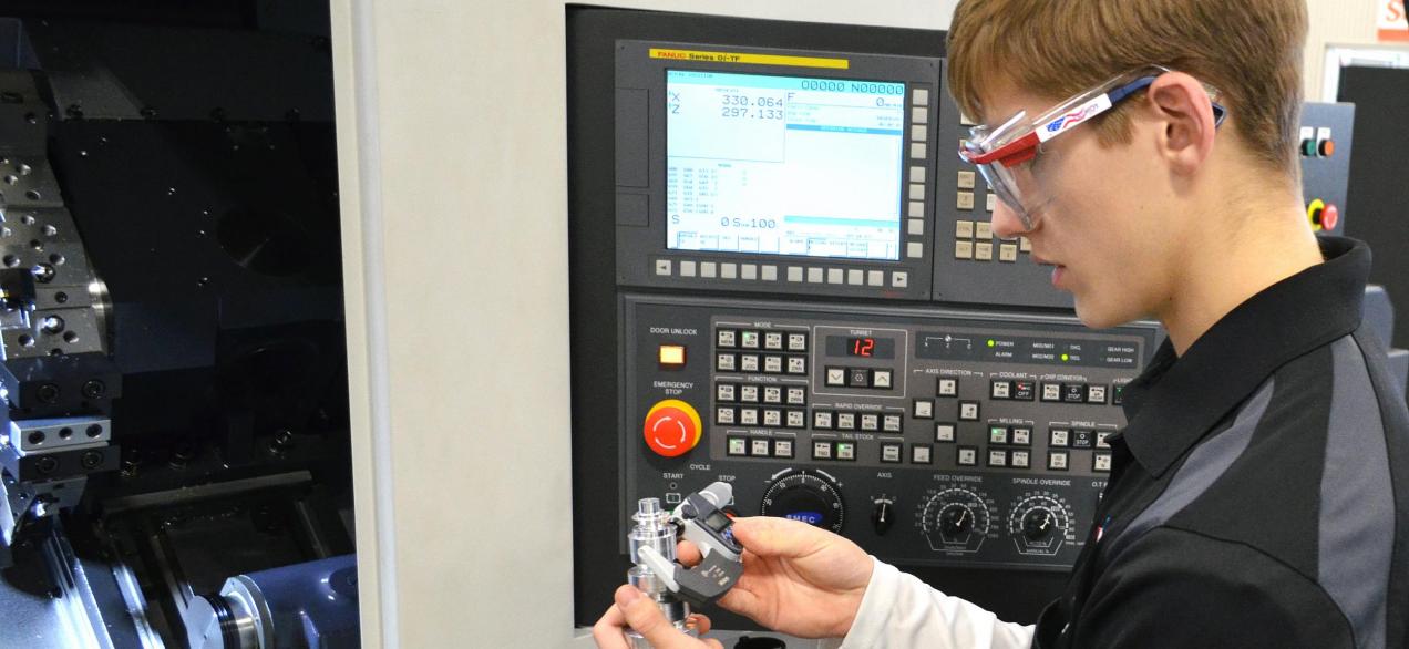 Student measures a part milled on a CNC machine